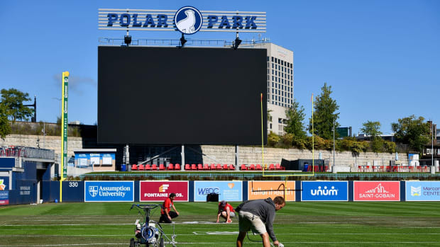 Workers paint yard lines on the field at Polar Park ahead of the college football game between Holy Cross and Bucknell.